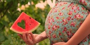 برش هندوانه در دست یک زن باردار